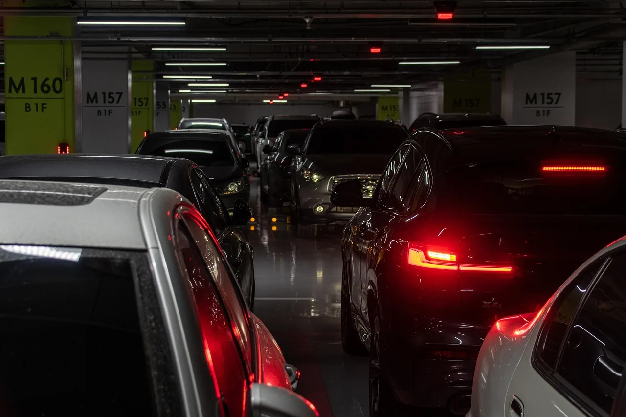 Samochody stojące w rzędzie w ciemnym wielopoziomowym parkingu podziemnym – parking przy lotnisku chopina